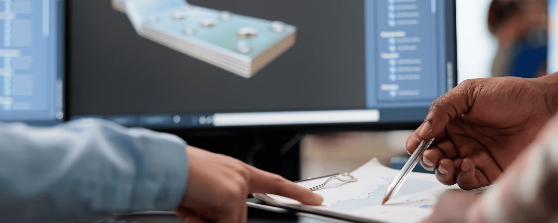 Two people reviewing technical drawing with 3D CAD model